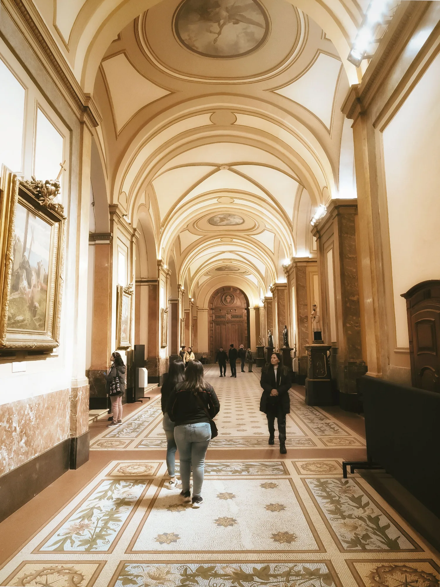 Interior de museo o galería, figura humana de espaldas observando una obra, luz suave.